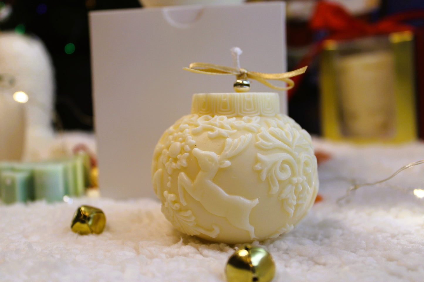 Obenansicht der cremefarbenen Weihnachtskerze mit goldener Schleife und Glöckchen.