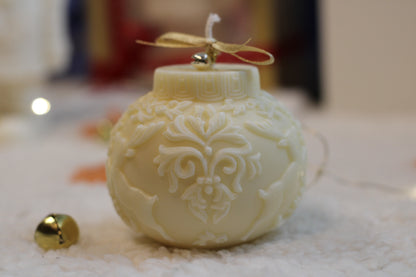 Handgefertigte runde cremefarbene Weihnachtskerze mit Rentier-Relief, goldener Schleife und Glöckchen auf festlich dekoriertem Hintergrund.